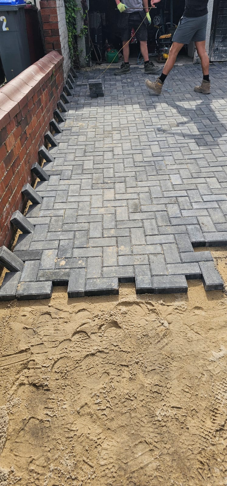 Block paving being laid in herringbone pattern over kiln-dried sand