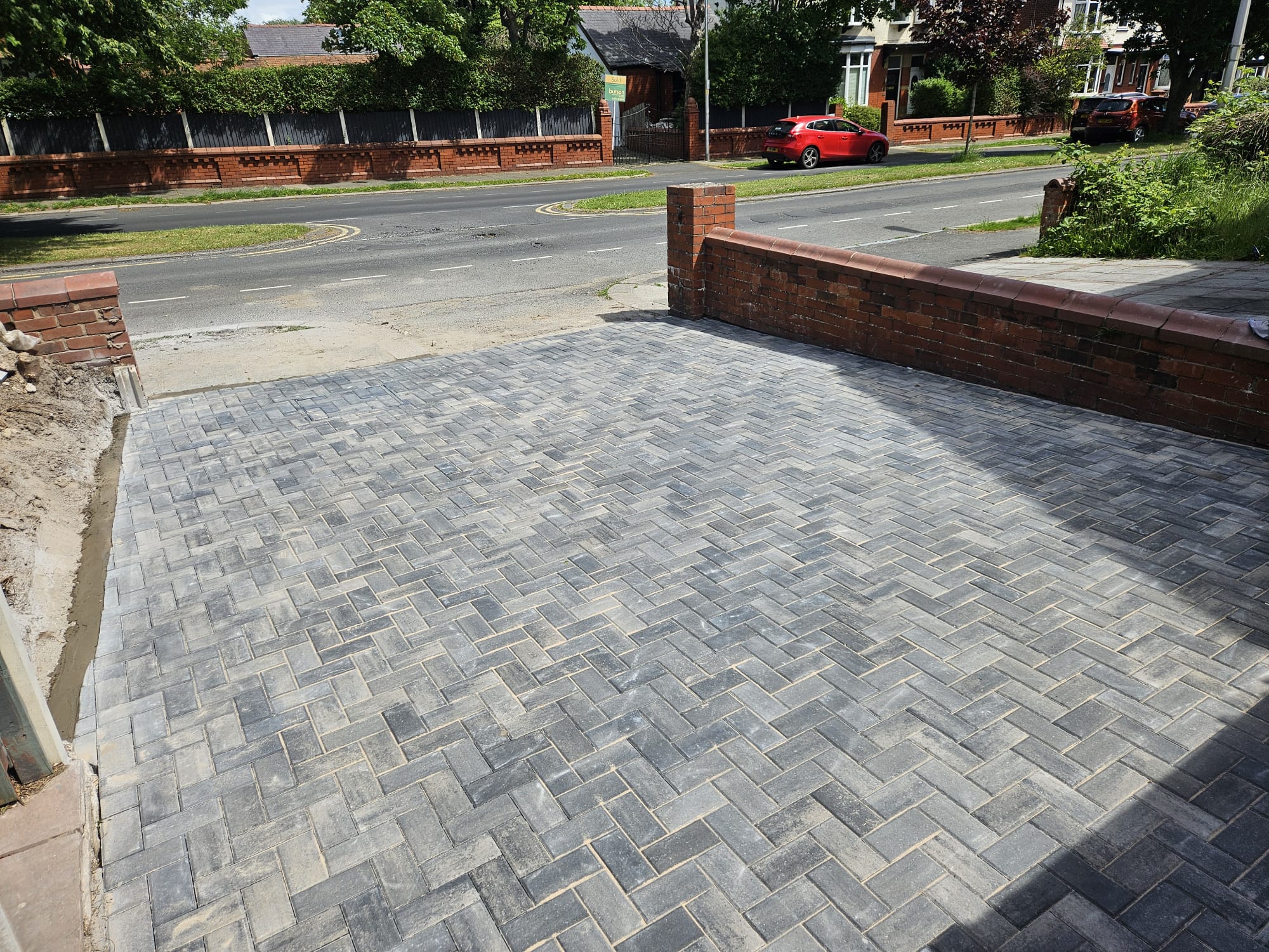 Block-paved driveway entrance with brick boundary wall onto the road