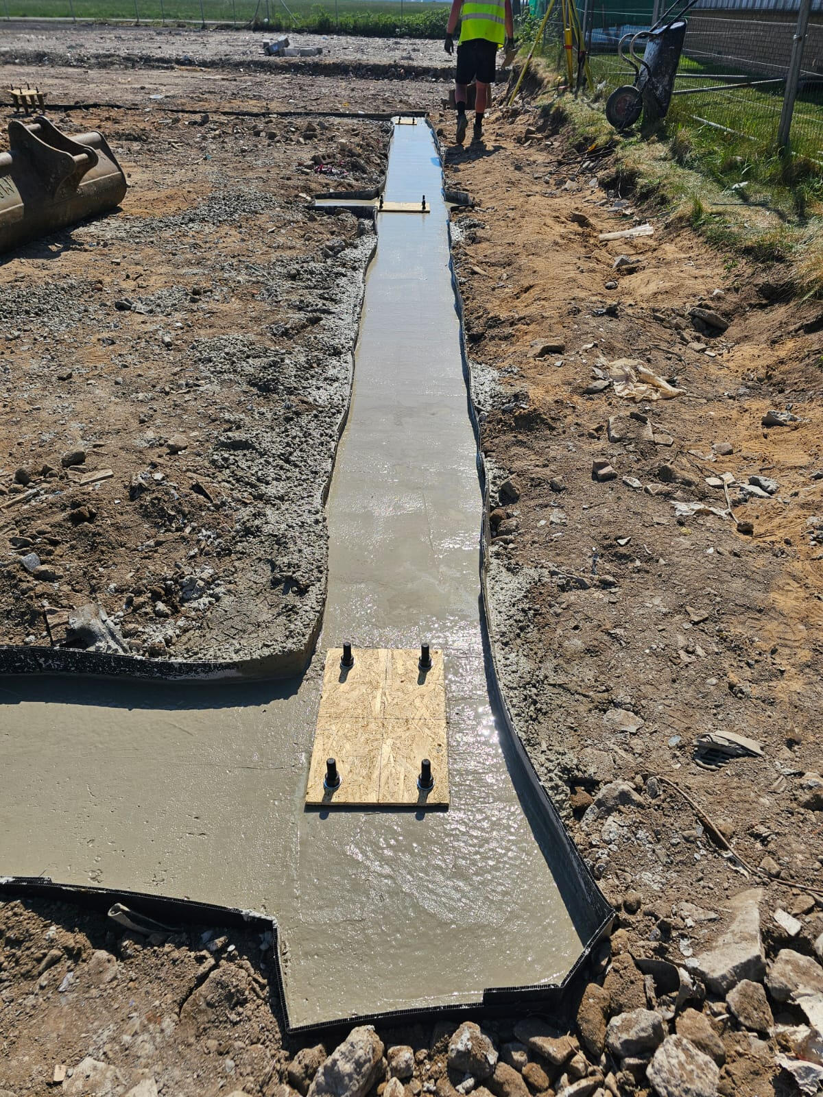 Freshly poured concrete strip foundation with holding-down bolts