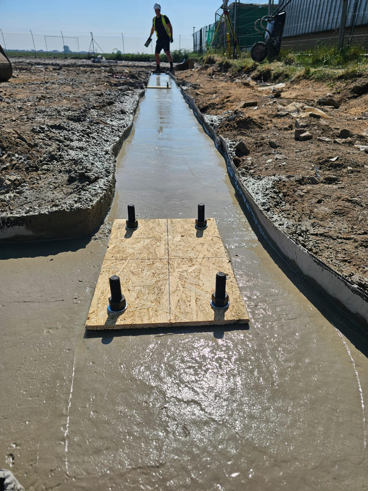 Cast-in holding-down bolts in a fresh concrete strip foundation