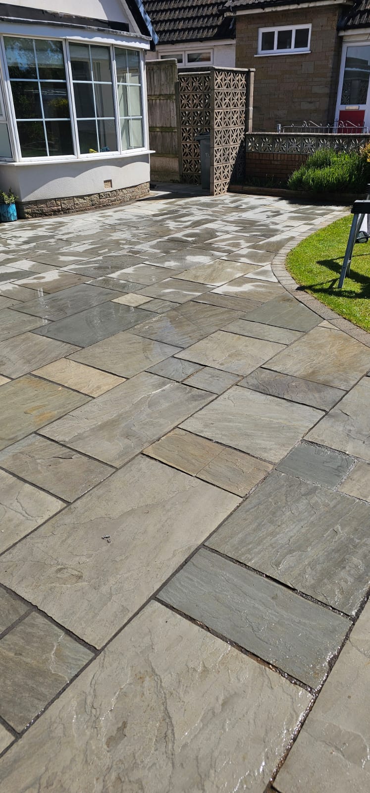 Indian sandstone patio curving onto lawn with cobble edging