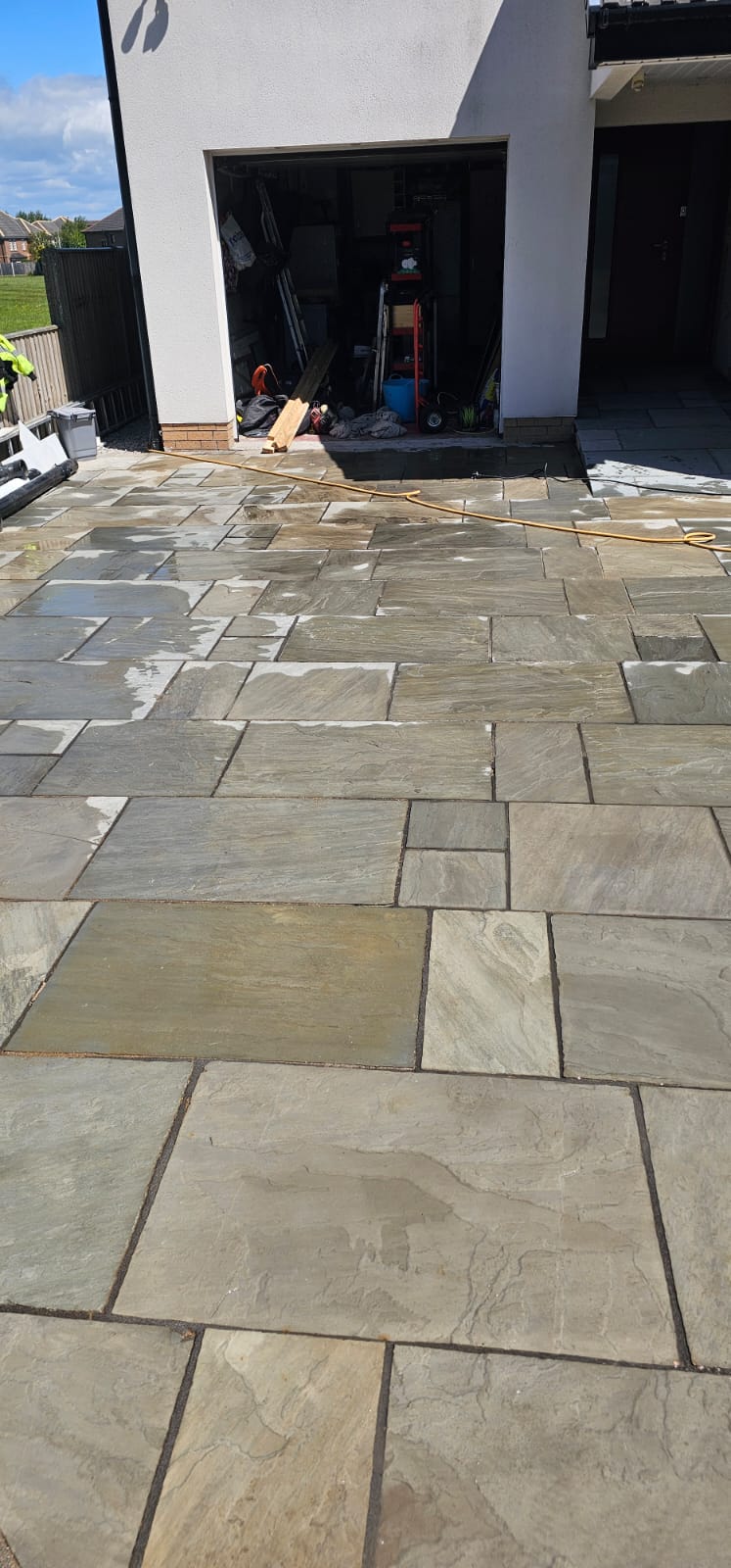 Wide Indian sandstone patio leading to garage door